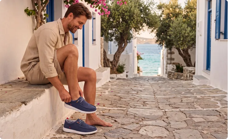 Mann zieht Fusion Schuhe in mediterraner Umgebung an