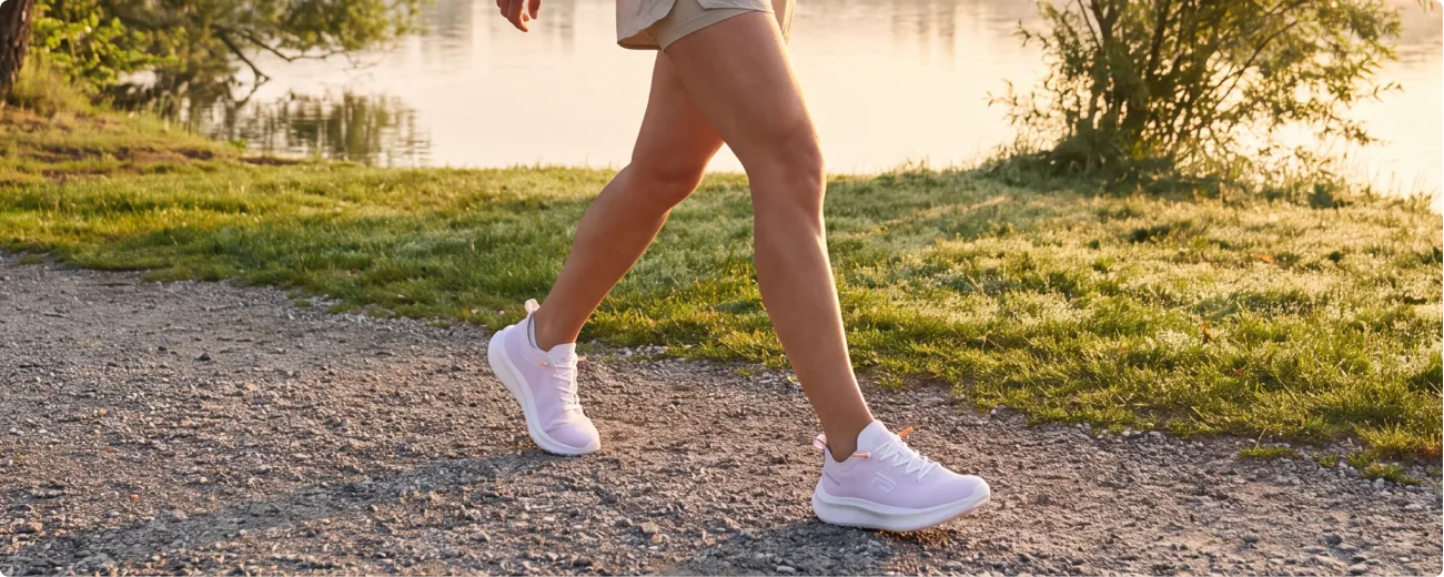 Frau trägt weiße Fusion Sportschuhe beim Spaziergang am Wasser