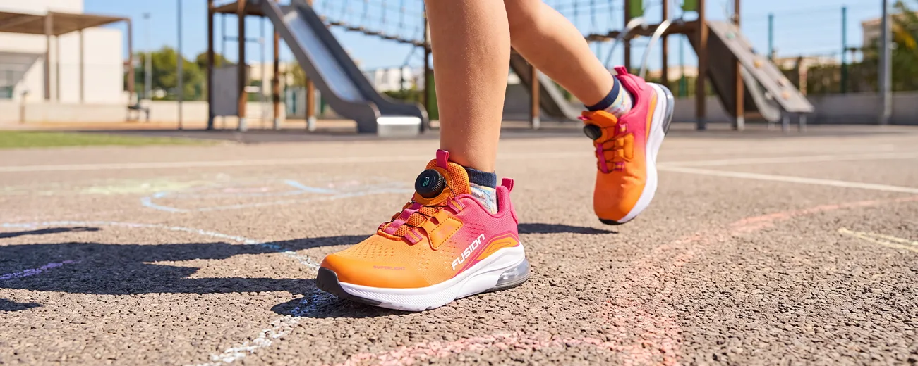 Frau trägt weiße Fusion Sportschuhe beim Spaziergang am Wasser