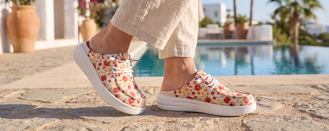 Frau trägt weiße Fusion Sportschuhe beim Spaziergang am Wasser